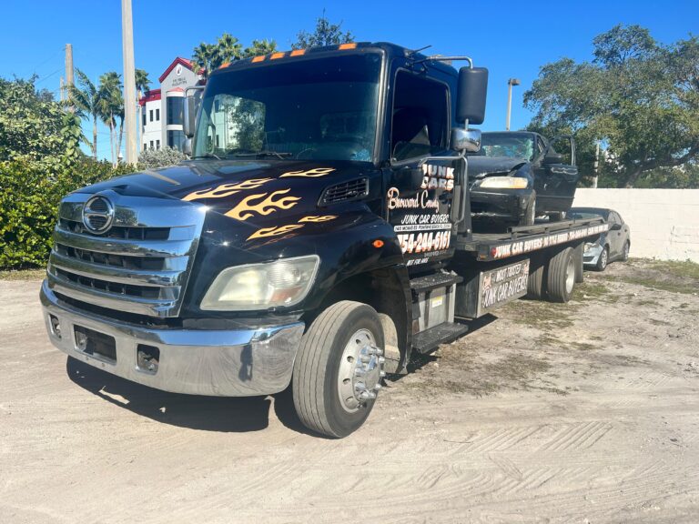 Tow truck carrying a junk car.